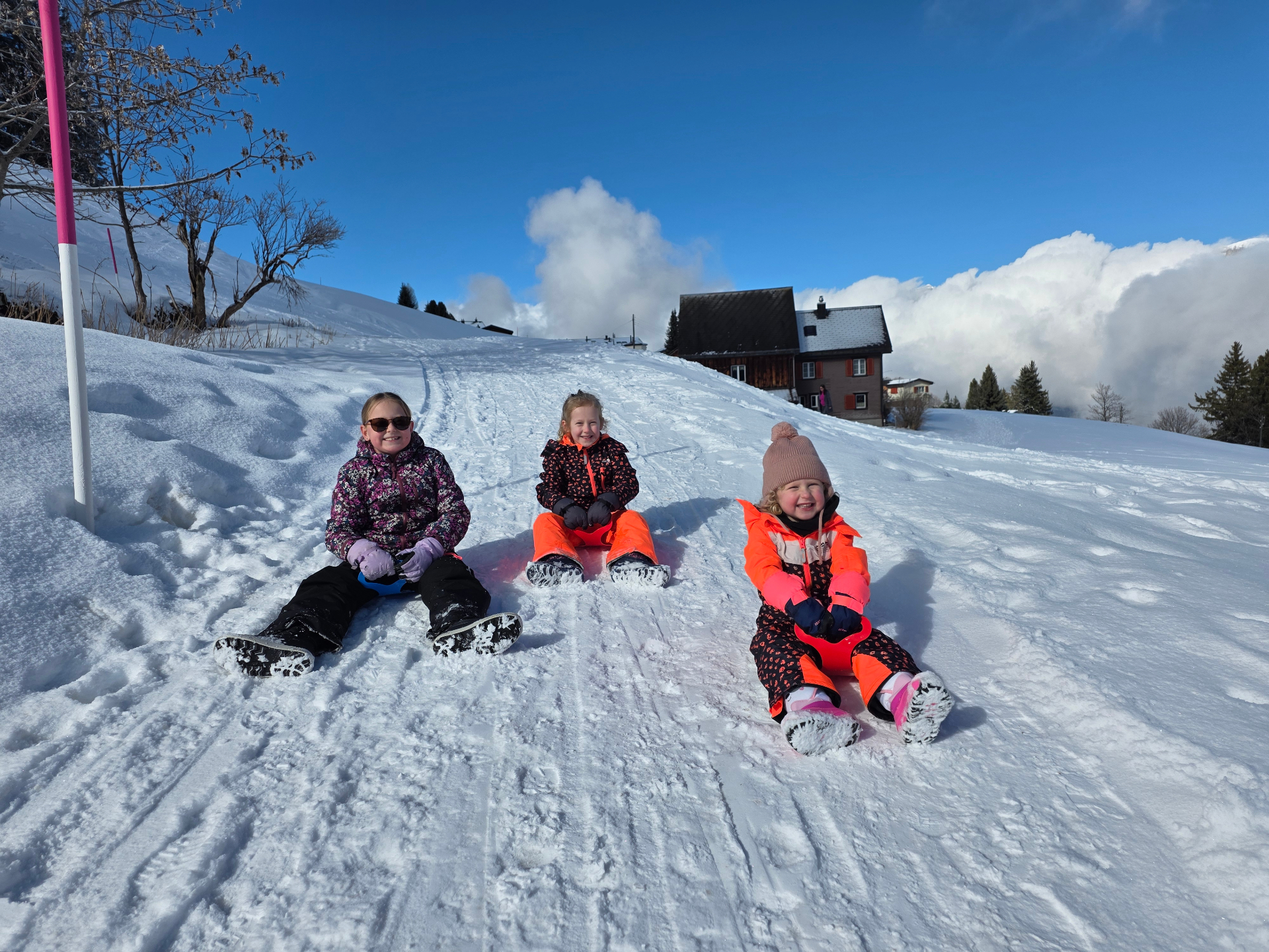 Kinderen genieten van het sleeën in de sneeuw bij Flumserberg