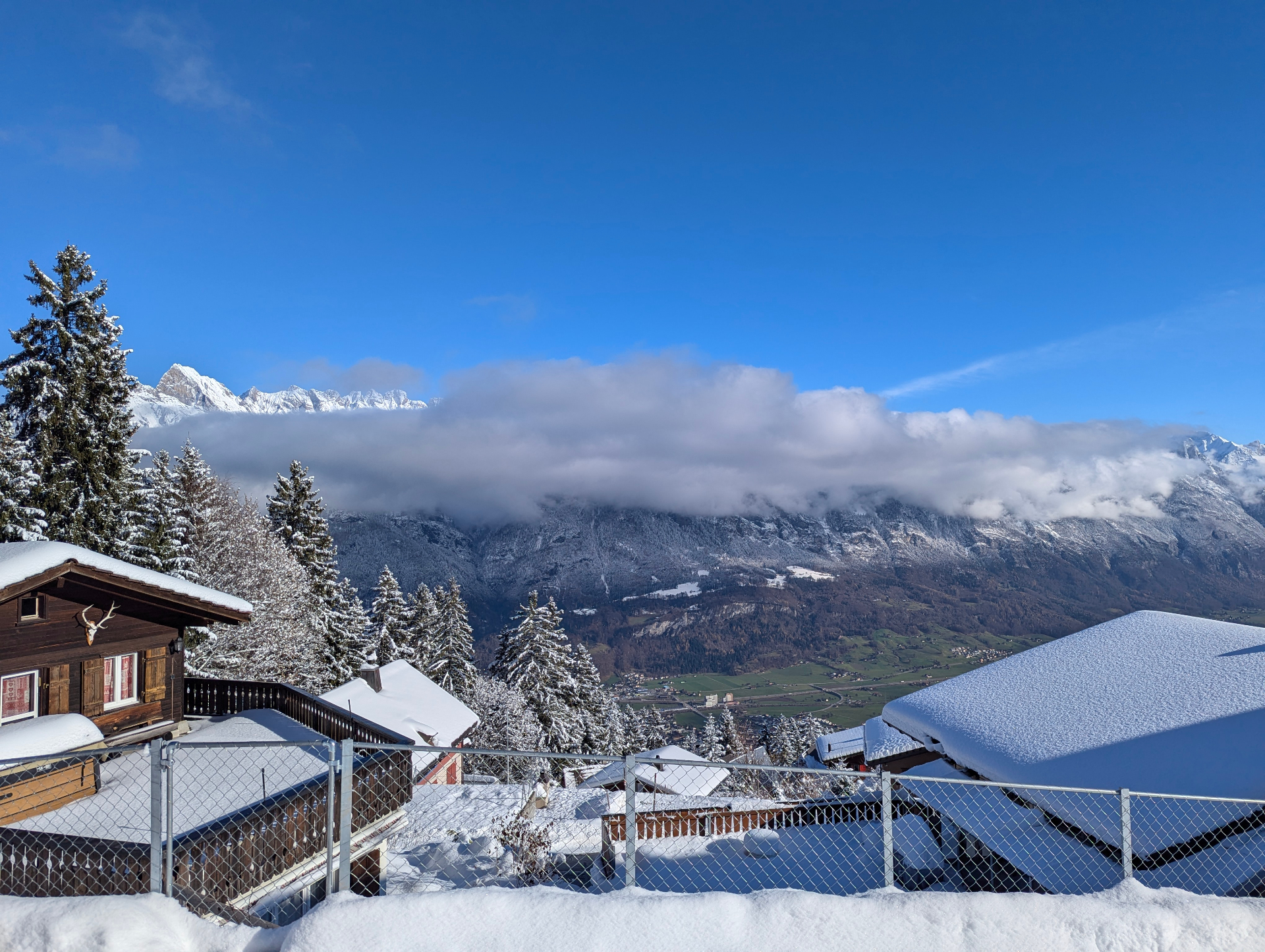 Besneeuwde chalets op de Flumserberg met wolken over de bergen